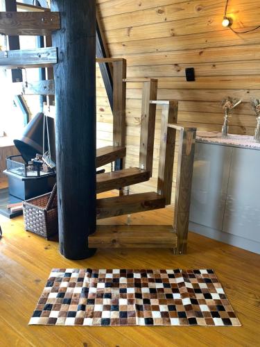 a wooden staircase in a room with a checkered floor at Chalé Alto do Morro 2 - conforto e vista deslumbrante in Rancho Queimado