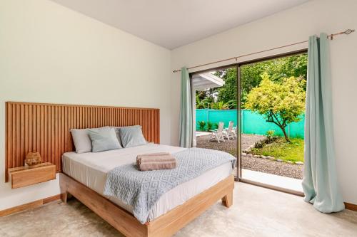 a bedroom with a bed and a large window at Villa Oropendola a 5 minutos de cahuita in Comadre