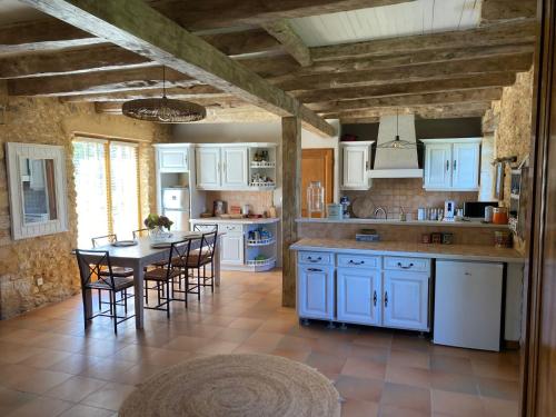 a kitchen with white cabinets and a table and chairs at Le Domaine de Camberoux La Petite Longère in Saint-Marcel-du-Périgord