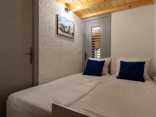 - un grand lit blanc avec des oreillers bleus dans l'établissement Superbe Studio Mezzanine Rénové au Cœur du Grand Bornand – 4 Couchages, Balcon, Proche Commerces et Ski - FR-1-458-162, au Grand-Bornand