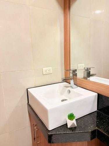 a bathroom with a white sink and a mirror at Sol y Confort Suites in Machala