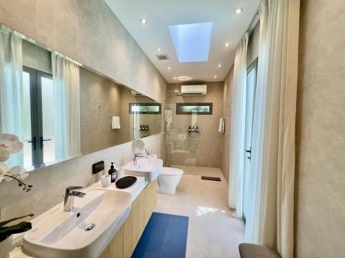 une salle de bain avec deux lavabos et un WC et un miroir dans l'établissement Bangtao villa with pool & rooftop terrace, à Ban Thalat Choeng Thale