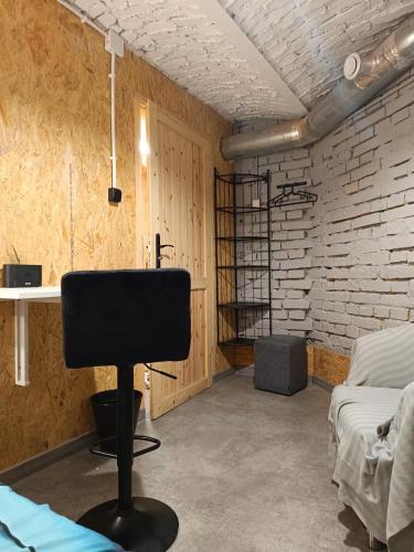 a room with a black chair and a brick wall at Room 1 industrial in Krakow