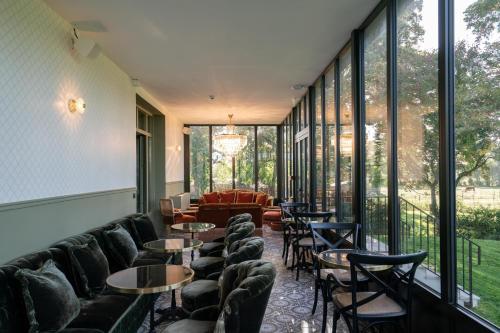 a room with chairs and tables and windows at Villa Edmond Hôtel & Spa - Maison Blanche Bièvres in Bièvres