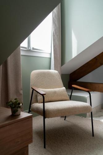 a chair sitting in a room next to a window at Villa Edmond Hôtel & Spa - Maison Blanche Bièvres in Bièvres