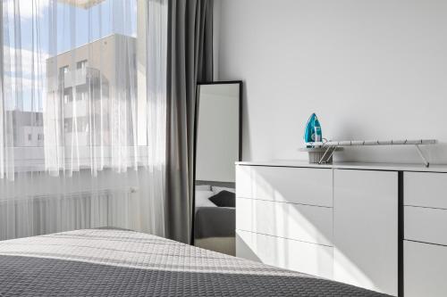 a white bedroom with a white dresser and a mirror at Bratislava Airport Apartment in M R Stefanik
