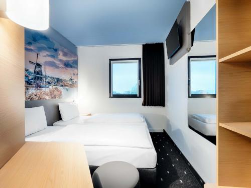 a hotel room with two beds and a tv at B&B Hotel Amsterdam-Zaandam in Zaandam