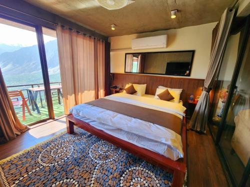 a bedroom with a bed and a large window at Hunza Hard Rock Resort in Baltit
