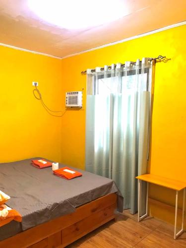 Una habitación amarilla con una cama y una ducha. en Three Sister's Inn, en Siquijor