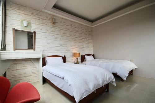 a bedroom with two beds and a tv on a wall at 潔坊琳居民宿 JayLin Home in Yuchi