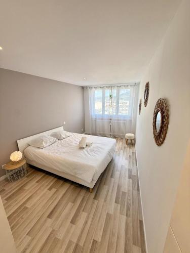una camera con letto bianco e pavimento in legno di Le Victoria I Balcon & garage, Plein-centre ad Aix-les-Bains