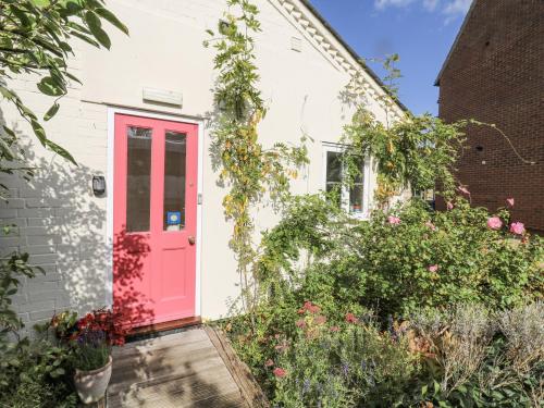 a pink door on a white house with flowers at Over Village Studio in Over