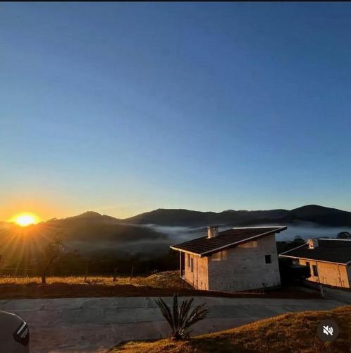 a house with the sunset in the background at Chalés Varandas da Serra in Monte Verde