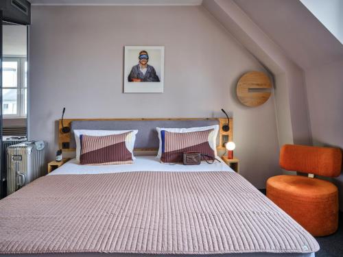 a bedroom with a large bed and a chair at Flemings Hotel Frankfurt-Central in Frankfurt/Main