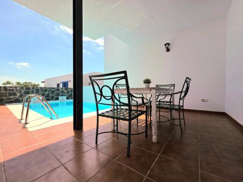 comedor con mesa, sillas y piscina en Villa Papagayo Mirage, en Playa Blanca