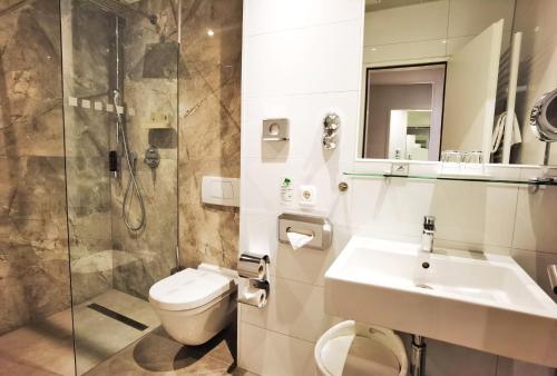 a bathroom with a toilet and a sink and a shower at Arthotel Munich in Munich