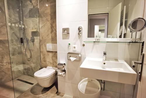 a bathroom with a sink and a toilet and a shower at Arthotel Munich in Munich