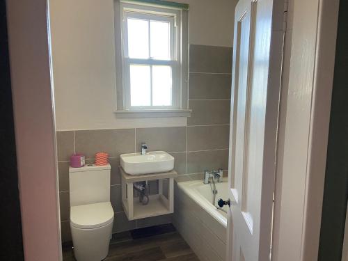 une salle de bain avec toilettes, lavabo et fenêtre dans l'établissement Cradle Cottage, à Crail