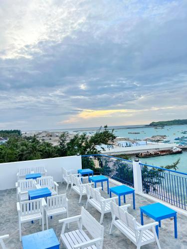 a row of white chairs and blue tables on a balcony at Babylon Hotel Phu Quy in Îlot du Sud
