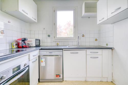 une cuisine avec des appareils électroménagers blancs et une fenêtre dans l'établissement Cocon Roseraie, à LʼHay-les-Roses