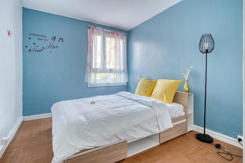 ein Schlafzimmer mit blauen Wänden und einem Bett mit gelben Kissen in der Unterkunft Cocon Roseraie in LʼHay-les-Roses