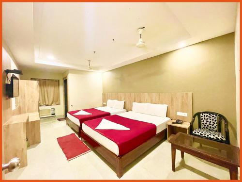 a bedroom with two beds and a chair in it at HOTEL PRIME J & K INN - NEAR SEA BEACH - Restaurant - #Lift And Parking Facilities - #fully Air Conditioned hotel at Prime Location - #BREAKFAST included -LUXURAY HOTEL IN PURI in Puri