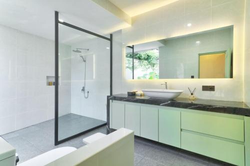 a bathroom with a sink and a glass shower at The Dutch Bungalow Seminyak in Seminyak