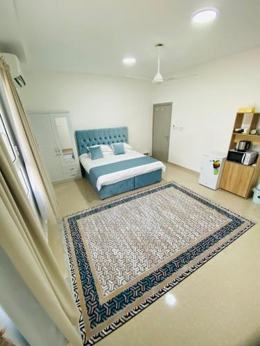 Un dormitorio con una cama y una alfombra en el suelo. en VIP Room3 in South alhail - Muscat, en Ḩayl Āl ‘Umayr