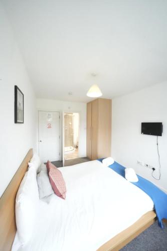 a bedroom with a large white bed and a television at Private on suites- Private Bathroom every room-1 Bus to Heathrow Airport in Harmondsworth