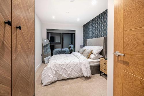 a bedroom with a bed and a wooden door at Luxury 2BR Penthouse-1, Private Terrace, City Center, Free Parking in Leeds