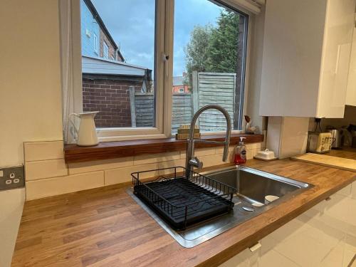 een keuken met een wastafel en een groot raam bij Mallison Cottage in Stalybridge