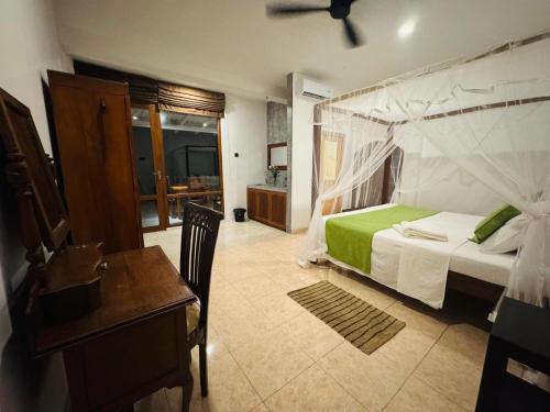 a bedroom with a bed and a table and a desk at Brinkhouse Guesthouse , Unawatuna beach in Unawatuna