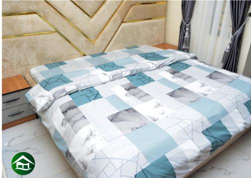 a bed with a blue and white quilt on it at Holy Eucharis Serviced Apartments in Lagos