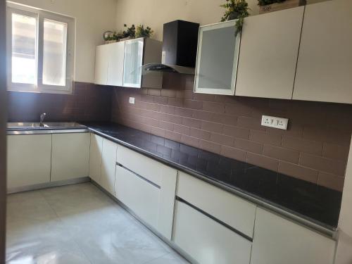 a kitchen with white cabinets and a black counter top at Sweethome in Lāndrān