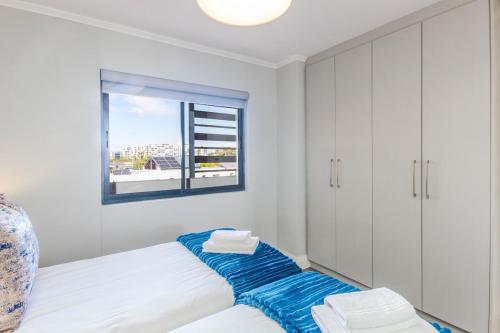a white bedroom with a bed with a window at Quayside 301 by CTHA in Cape Town