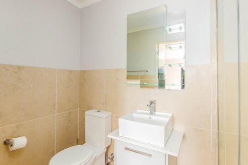 a bathroom with a toilet and a sink and a mirror at Quayside 301 by CTHA in Cape Town