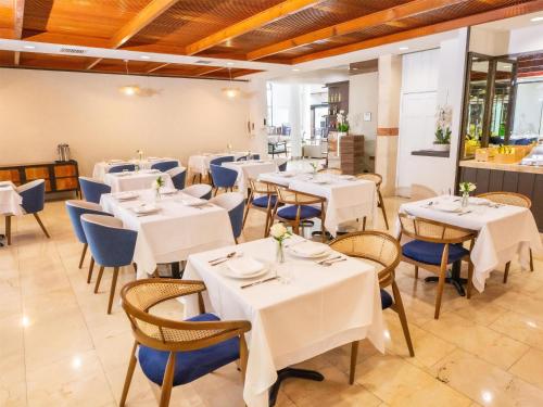 a restaurant with white tables and blue chairs at Logis Auberge La Diege in Capdenac-Gare