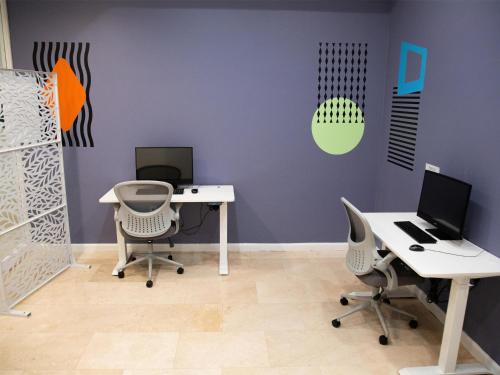 an office with two desks and two computers on a purple wall at Logis Auberge La Diege in Capdenac-Gare