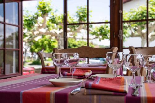 a table with wine glasses on top of it at Logis Hôtel Baratxartea in Sare