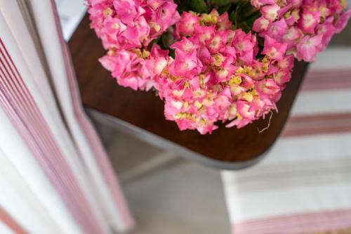 a vase filled with pink flowers next to a book at Logis Hôtel Baratxartea in Sare
