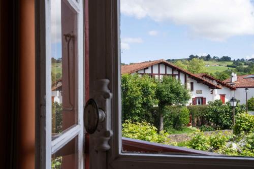 an open window with a view of a house at Logis Hôtel Baratxartea in Sare