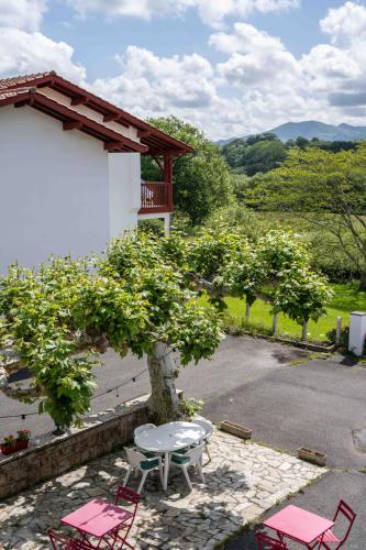 a patio with a table and chairs and trees at Logis Hôtel Baratxartea in Sare