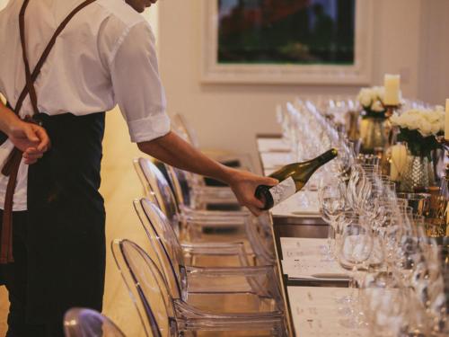a man opening a bottle of wine at a table at The Johnson Brisbane - Art Series in Brisbane