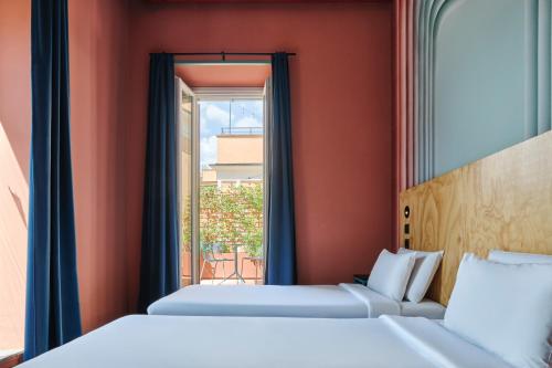 two beds in a room with a window at JO&JOE ROMA in Rome