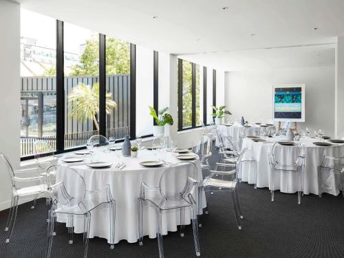 a room with white tables and chairs and windows at The Johnson Brisbane - Art Series in Brisbane
