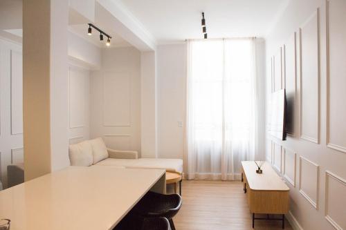 Habitación blanca con sofá y mesa en The Burg Collection - Suit One, en Ciudad del Cabo
