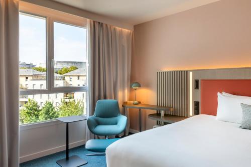 a hotel room with a bed and a chair and a window at Courtyard by Marriott Paris Saint Denis in Saint-Denis
