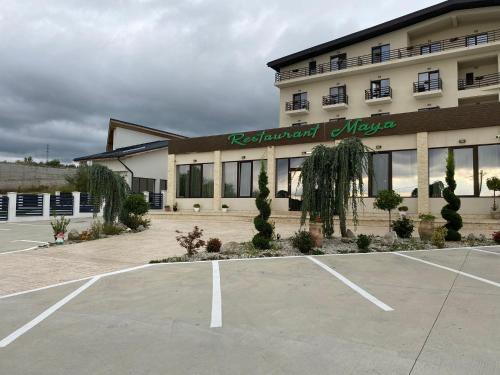 a building with a parking lot in front of it at Hotel Maya in Horezu