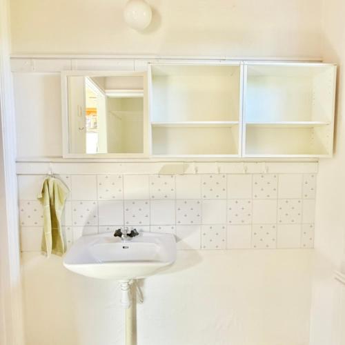 a white bathroom with a sink and a mirror at Light-filled and spacious villa on Vrångö Island in Vrångö