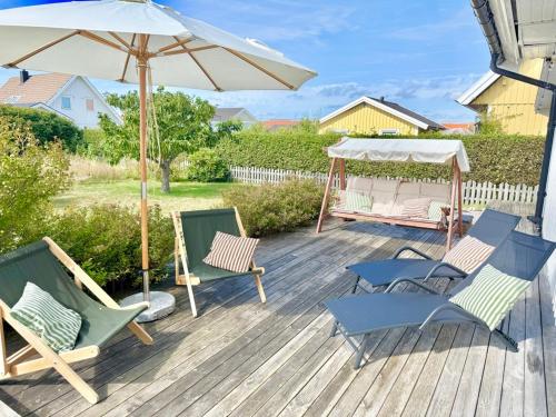 a deck with chairs and an umbrella and a gazebo at Light-filled and spacious villa on Vrångö Island in Vrångö